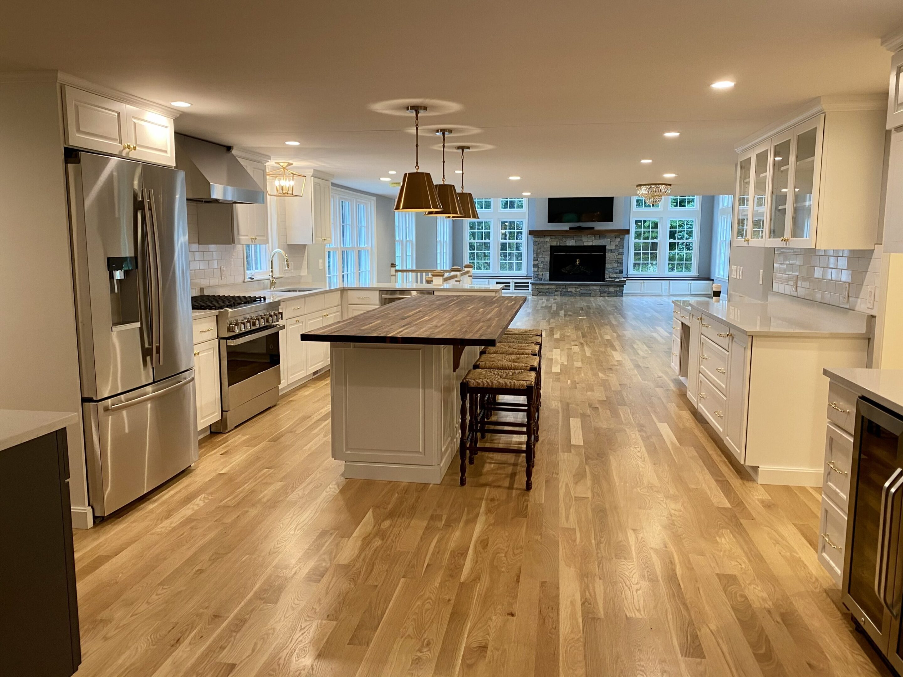 A large kitchen with wooden floors and white cabinets.